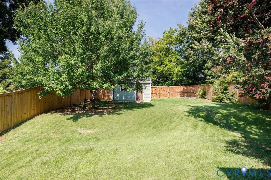808 W 47th Street, Richmond, VA 23225 Expansive grassy yard with mature trees, privacy fencing, and a storage shed