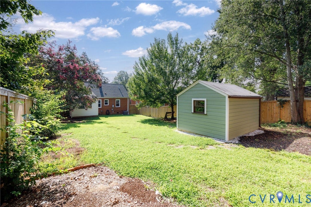 808 W 47th Street, Richmond, VA 23225 Expansive fenced backyard with established trees, a manicured lawn, and a detached storage shed