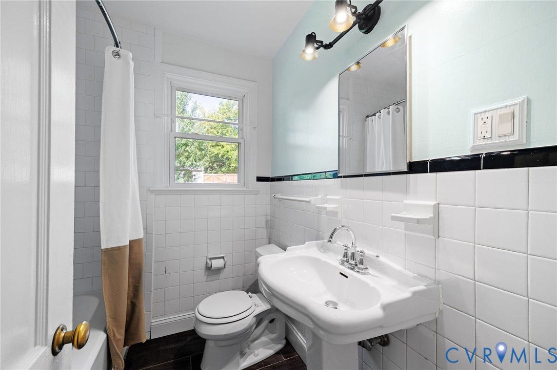 808 W 47th Street, Richmond, VA 23225 Pedestal sink with chrome fixtures, white square tile walls, wood-finish flooring, and a mirrored vanity
