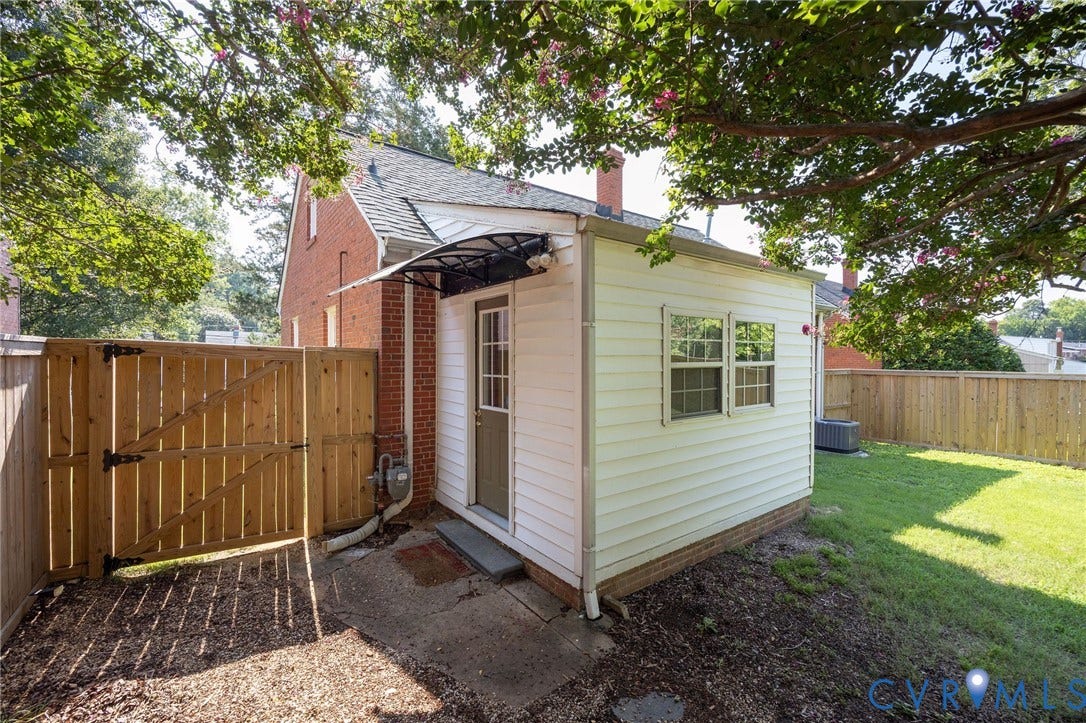 808 W 47th Street, Richmond, VA 23225 Outbuilding with white siding and window, covered entryway, and a wooden privacy fence
