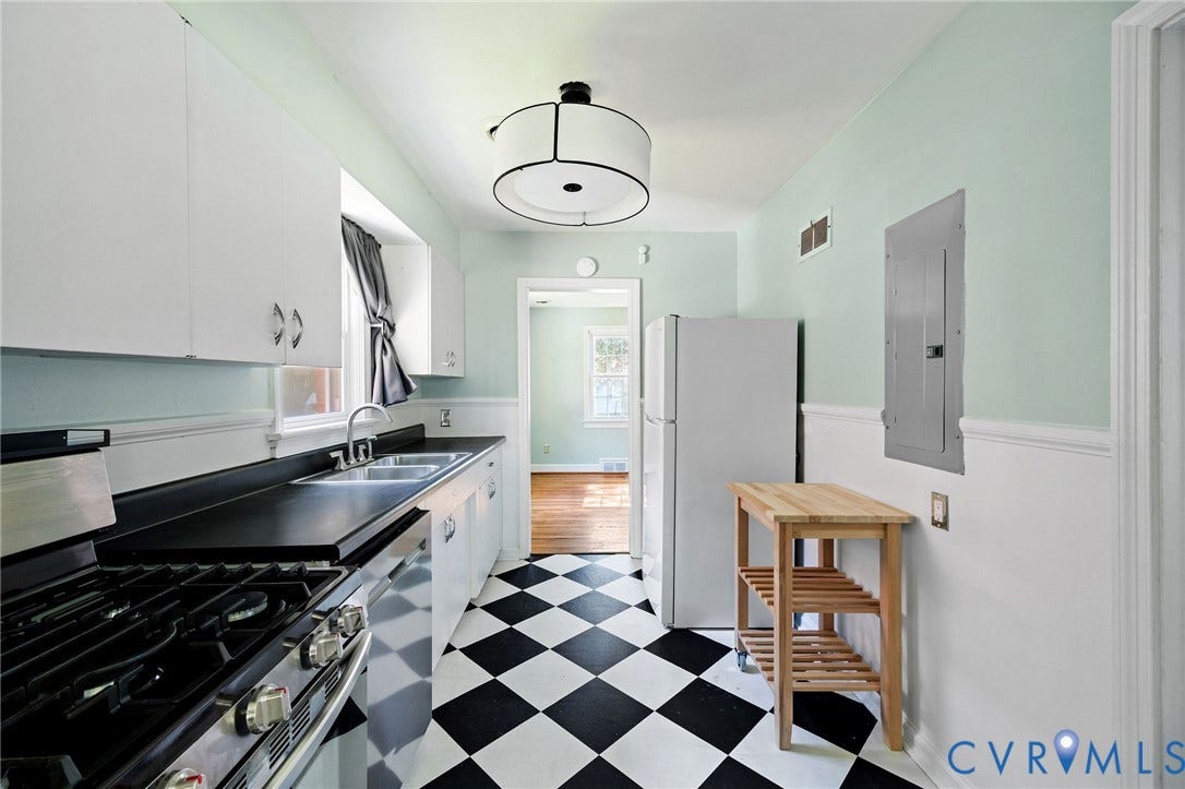 808 W 47th Street, Richmond, VA 23225 Kitchen featuring checkerboard flooring, white cabinetry, a double basin sink, and black countertops