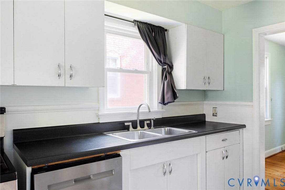 808 W 47th Street, Richmond, VA 23225 White cabinetry, stainless steel sink, black countertops, stainless steel dishwasher, and wood-finish flooring