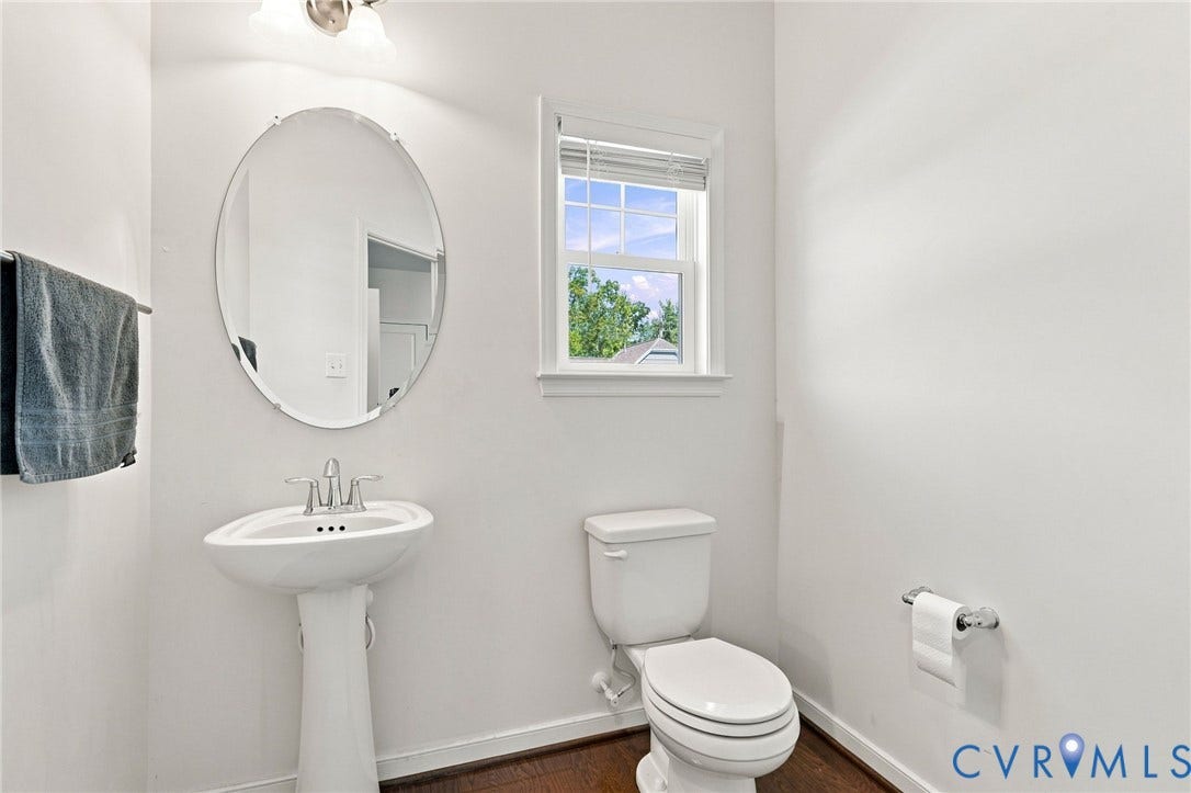 6400 Richwood Trail, Aston Oaks (Section 1), Chesterfield, VA 23120 Pedestal sink with chrome faucet, oval mirror, window with white blinds, white toilet, and wood-finish flooring
