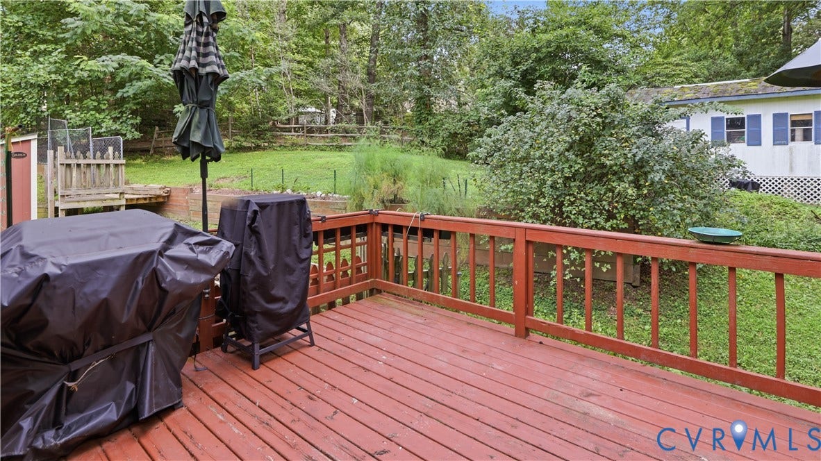 11201 Monday Way, Chesterfield, VA 23112 Expansive wooden deck with a red stain finish, featuring a matching railing and a surrounding green landscape
