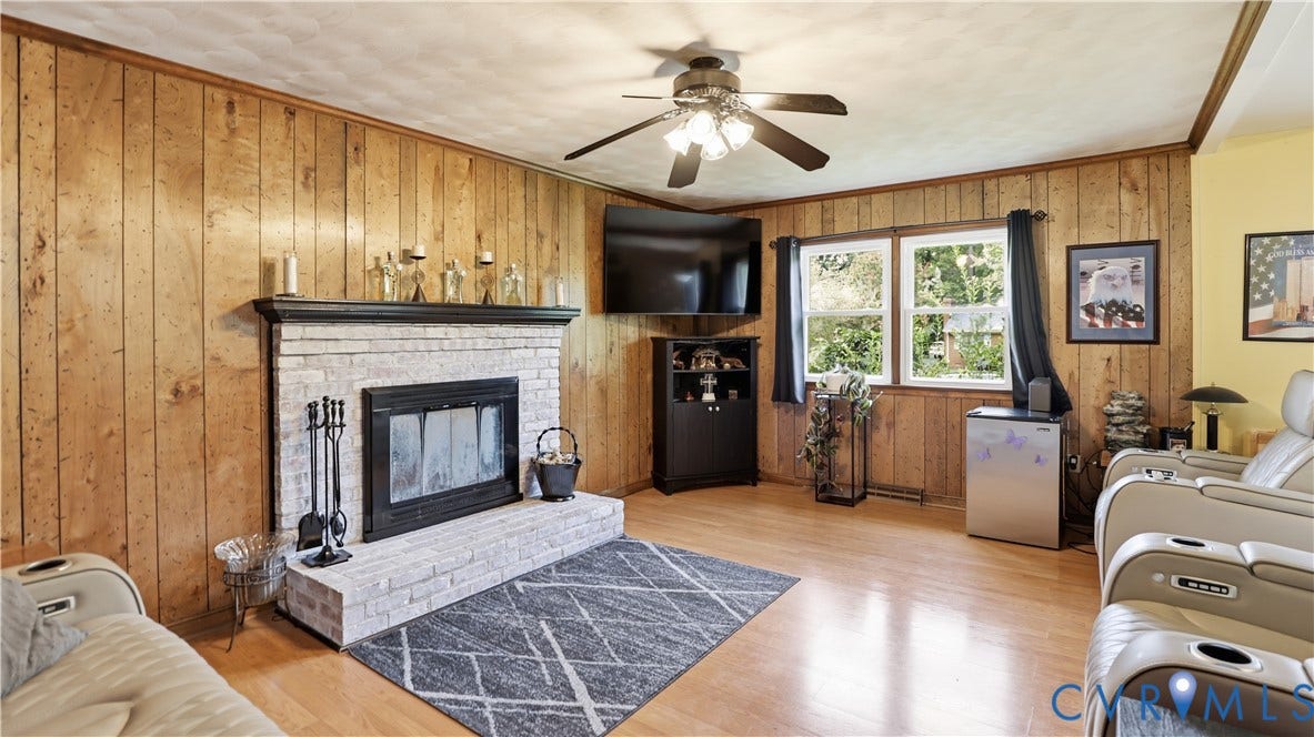 11201 Monday Way, Chesterfield, VA 23112 Brick fireplace with a dark mantel, wood-finish flooring, wood paneling, and a ceiling fan with integrated lighting
