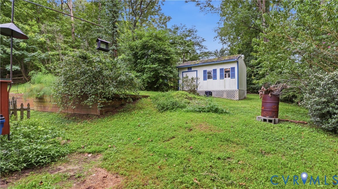 11201 Monday Way, Chesterfield, VA 23112 Detached storage shed with blue window shutters, set on a grassy expanse with mature trees