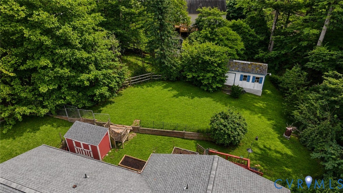 11201 Monday Way, Chesterfield, VA 23112 Expansive green lawn surrounded by mature trees, featuring a red storage shed, a white storage shed with blue shutters, and a wooden fence