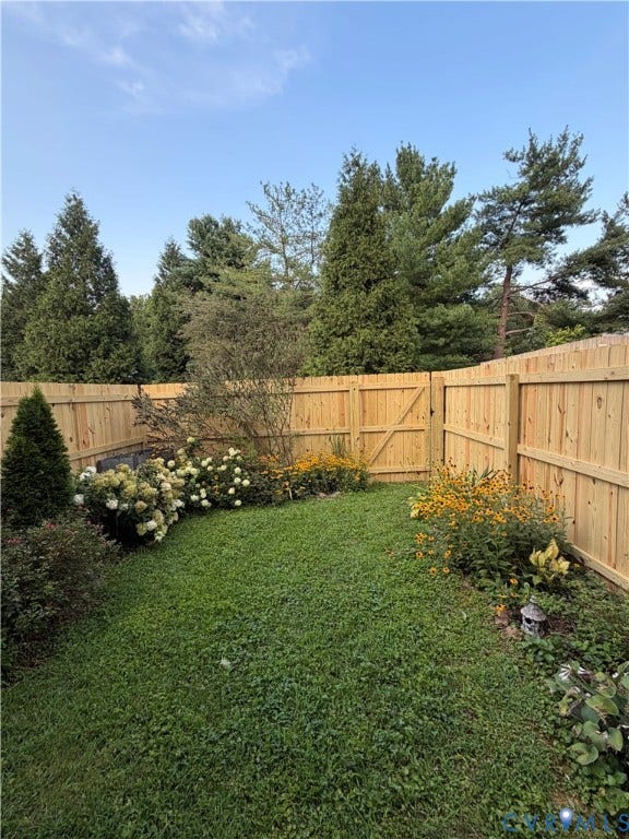 Private backyard with wood fencing, a gate, and diverse plantings