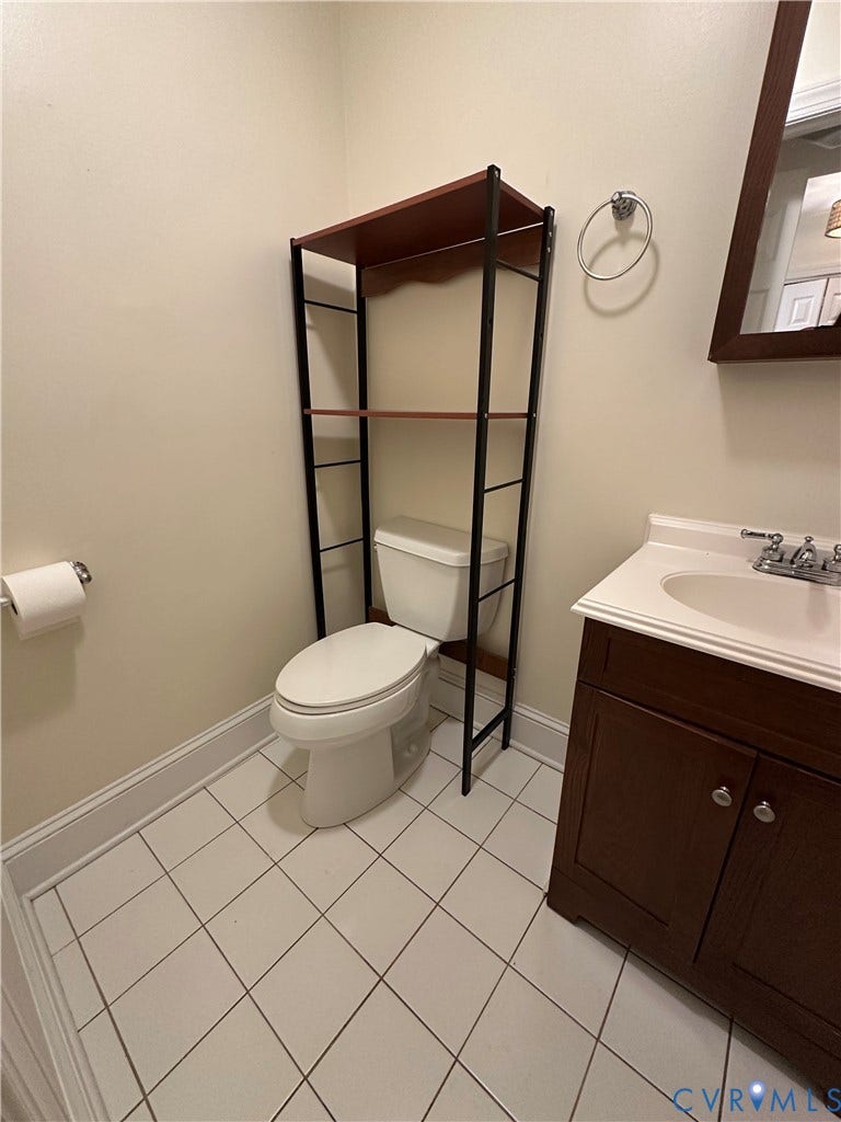 522.5 N 1st Street, Richmond, VA 23219 White tile flooring, single vanity with wood-finish cabinetry, and a wall-mounted mirror