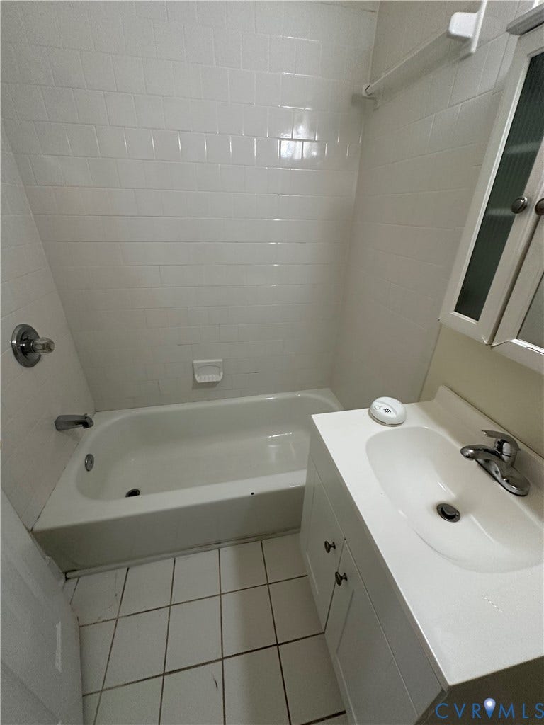 522.5 N 1st Street, Richmond, VA 23219 White subway tile shower surround, integrated bathtub, white square floor tiles, vanity with white cabinet doors, and a single basin sink