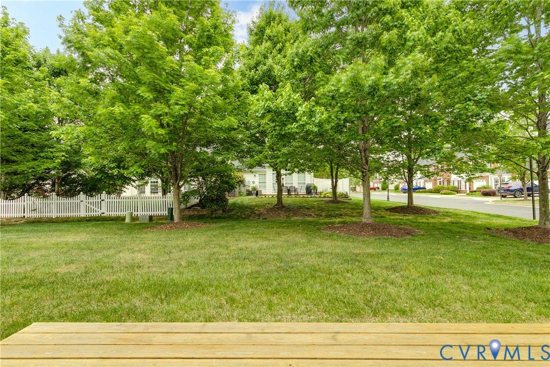 10607 Gate House Court, Glen Allen, VA 23059 Expansive grassy yard with mature trees, a white picket fence, and a wood plank deck