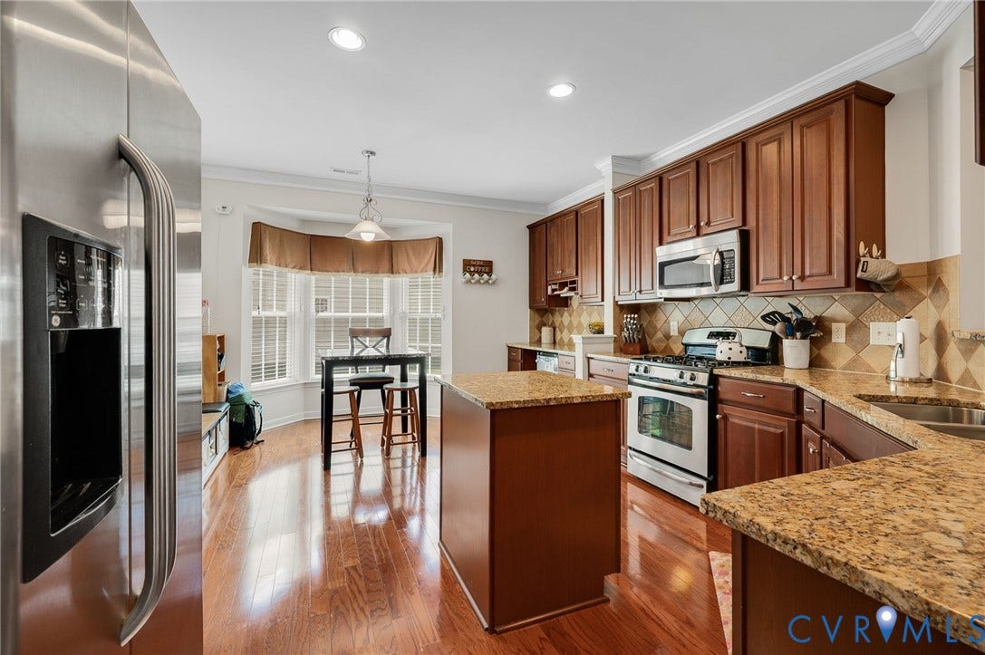 2811 Murano Way, The Villas At Hunton Park, Glen Allen, VA 23059 Chef's kitchen featuring warm wood cabinetry, granite countertops, stainless steel appliances including a French-door refrigerator, and a center island with seating