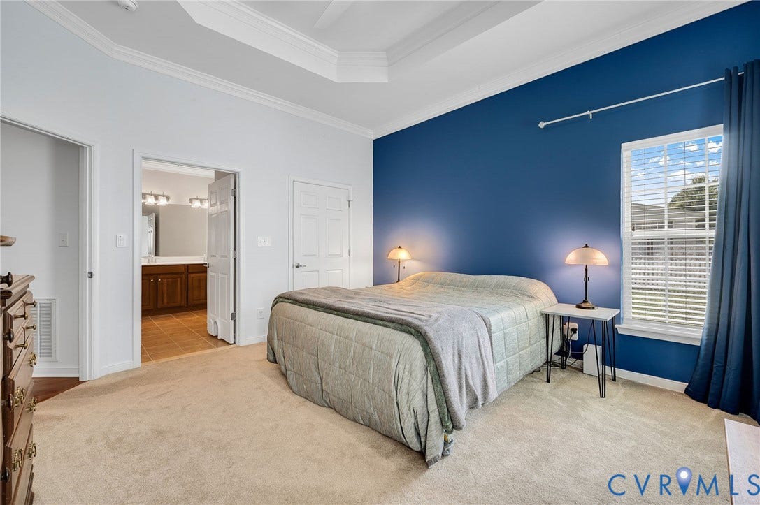 2811 Murano Way, The Villas At Hunton Park, Glen Allen, VA 23059 Spacious primary bedroom featuring a coffered ceiling, rich blue accent wall with paired bedside sconces, carpeted flooring, and direct access to an ensuite bathroom with wood cabinetry and vanity lighting