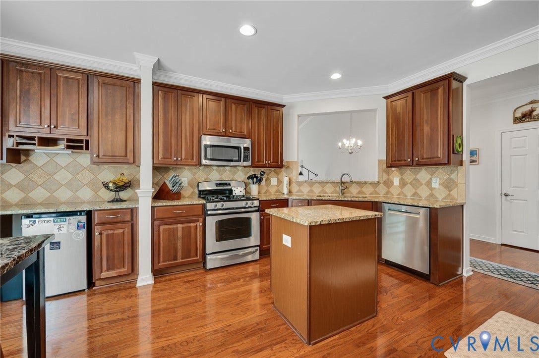 2811 Murano Way, The Villas At Hunton Park, Glen Allen, VA 23059 Chef's kitchen featuring warm wood cabinetry, stainless steel appliances, tile backsplash, and a substantial center island with seating