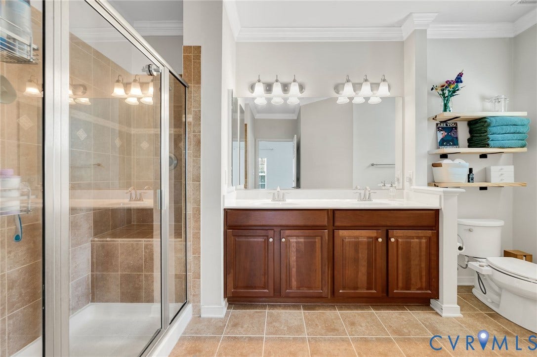 2811 Murano Way, The Villas At Hunton Park, Glen Allen, VA 23059 Spa-inspired primary bathroom featuring a double vanity with rich wood cabinetry, dual illuminated mirrors, and ceramic tile flooring