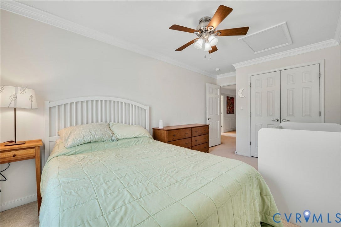 2811 Murano Way, The Villas At Hunton Park, Glen Allen, VA 23059 Serene primary bedroom showcasing a white arched headboard, wood-finish nightstands, ceiling fan with integrated lighting, and carpeted flooring