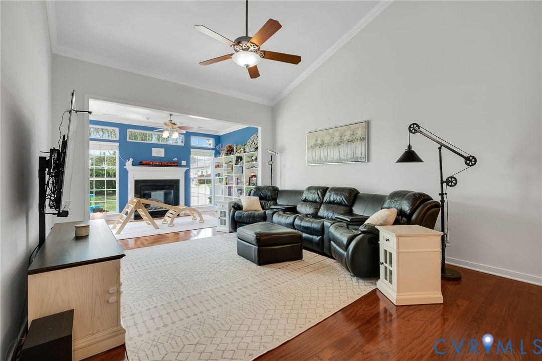 2811 Murano Way, The Villas At Hunton Park, Glen Allen, VA 23059 Spacious living area featuring a curved leather sectional, wood-finish flooring in select zones, and neutral carpet throughout