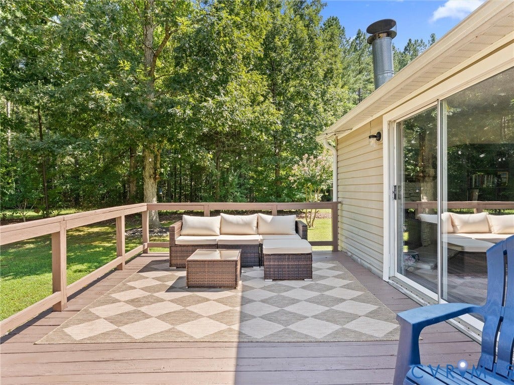4554 Powhatan Lakes Road, Powhatan, VA 23139 Expansive composite deck with geometric patterned hardscape, wooden railing, and integrated outdoor seating area overlooking mature wooded landscape