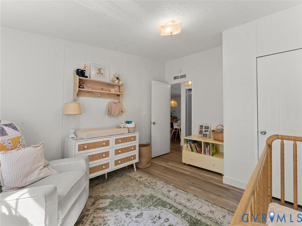 4554 Powhatan Lakes Road, Powhatan, VA 23139 Bright secondary bedroom featuring wood-finish flooring, built-in wooden dresser with multiple drawers, wooden shelving with hooks, and mirrored closet doors