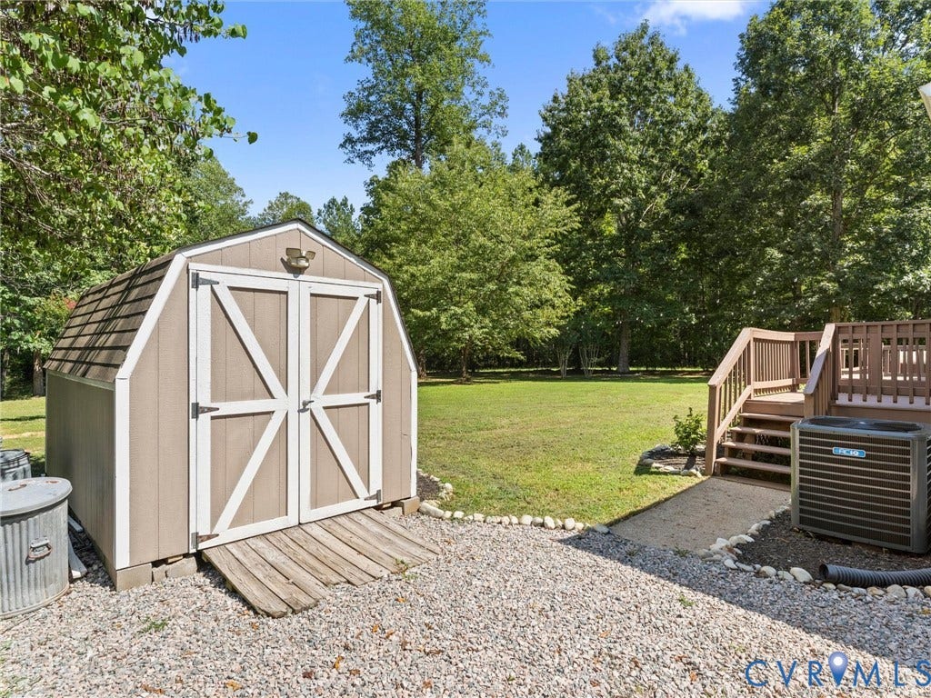 4554 Powhatan Lakes Road, Powhatan, VA 23139 Expansive backyard featuring a manicured lawn, a detached storage shed, and a multi-level wood deck