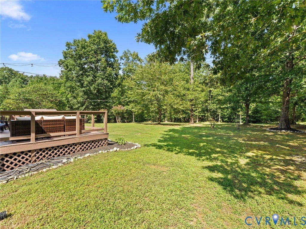 4554 Powhatan Lakes Road, Powhatan, VA 23139 Expansive grounds featuring a manicured lawn with mature shade trees and a covered outdoor structure with lattice detailing and wood-finish construction, offering ample space for recreation and entertaining