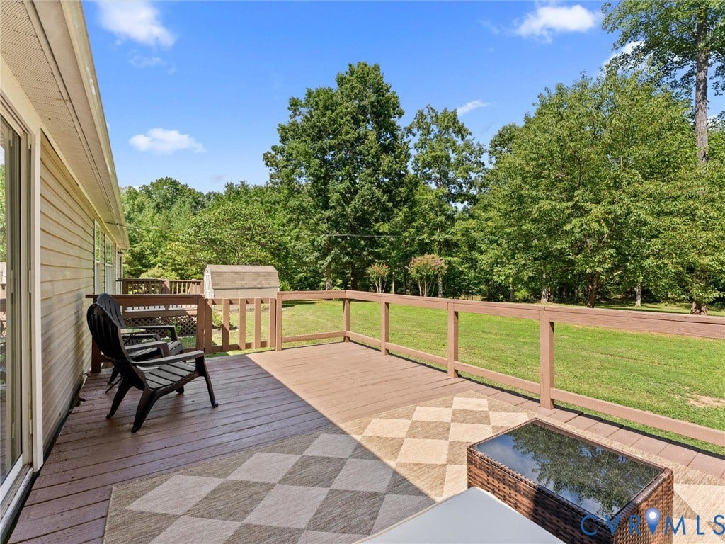 4554 Powhatan Lakes Road, Powhatan, VA 23139 Expansive composite deck featuring geometric patterned hardscaping, wood-finish railings with metal balusters, and direct access to manicured lawn bordered by mature trees