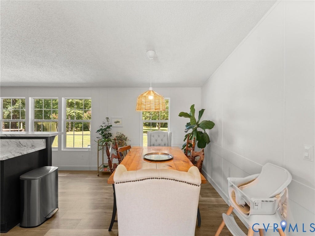 4554 Powhatan Lakes Road, Powhatan, VA 23139 Bright dining area with abundant natural light from multiple French doors and transom windows, wood-finish flooring, and pendant lighting fixture