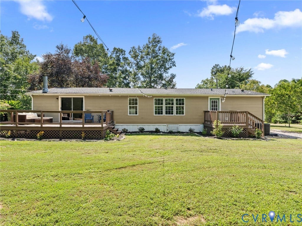 4554 Powhatan Lakes Road, Powhatan, VA 23139 Spacious manufactured home featuring a neutral tan exterior with multiple windows, expansive front lawn with mature landscaping, covered front porch, and rear deck access