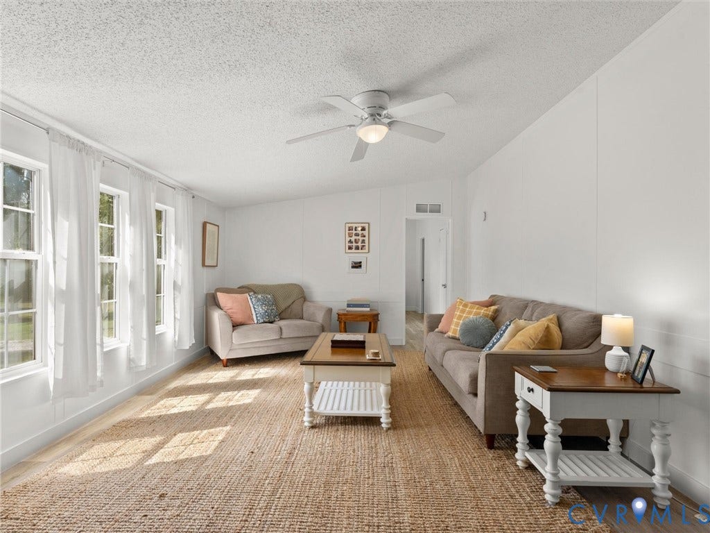 4554 Powhatan Lakes Road, Powhatan, VA 23139 Spacious living area featuring multiple windows, wood-finish flooring, a ceiling fan, and white panel walls