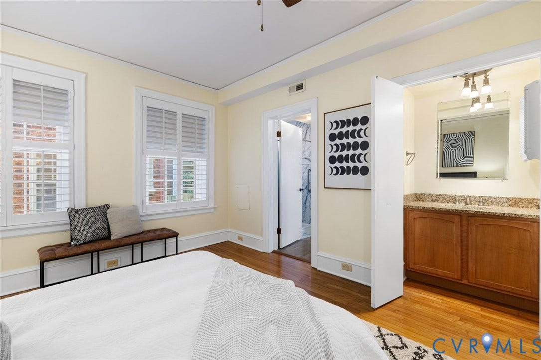 Spacious primary bedroom featuring hardwood flooring, SEPARATE DEDICATED VANITY, cream-toned walls, and abundant natural light from multiple windows with plantation shutters