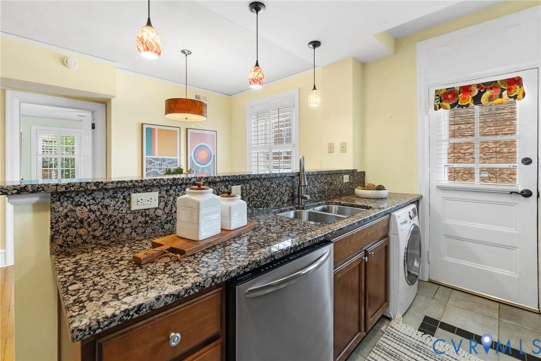 Wood-finish cabinetry, granite countertops, tile backsplash, and stainless steel gas range with microwave