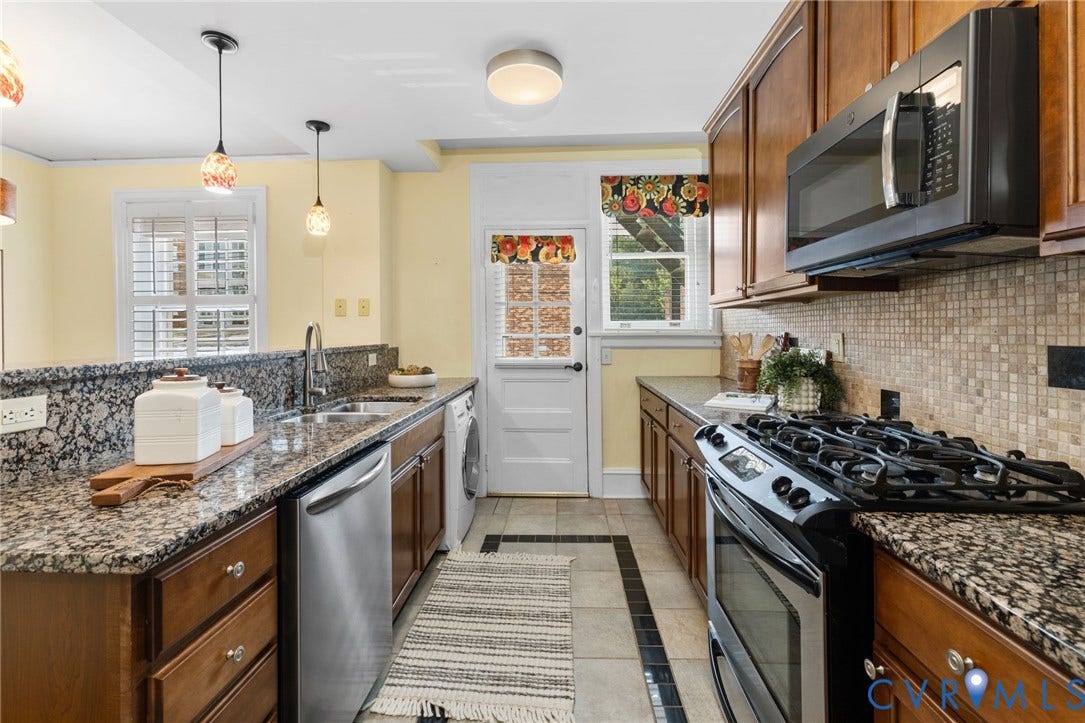 Wood-finish cabinetry, granite countertops, tile backsplash, and stainless steel gas range with microwave