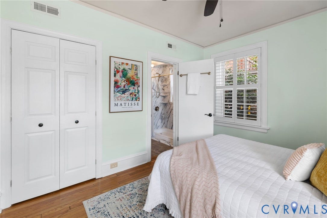 Hardwood flooring, FULL SIZED WALK IN CLOSET, painted walls, white trim, two windows with plantation shutters, and a ceiling fan