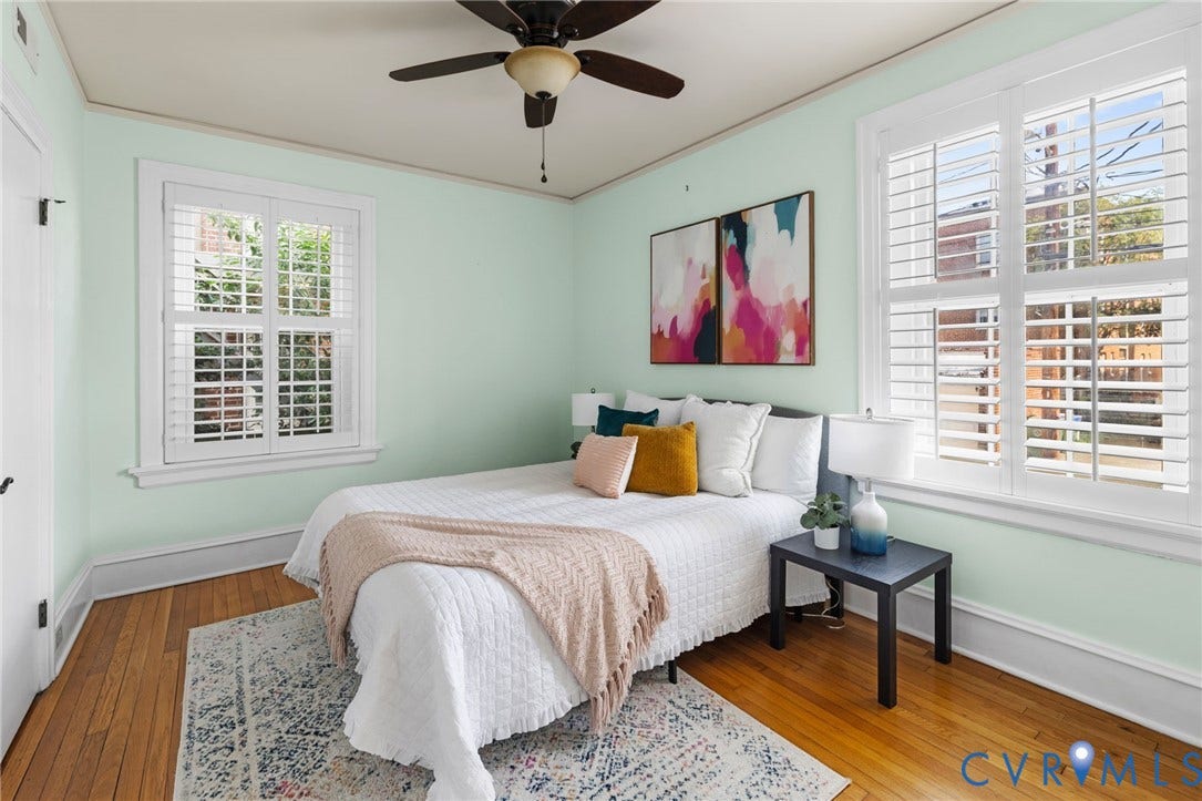 Hardwood flooring, FULL SIZED WALK IN CLOSET, painted walls, white trim, two windows with plantation shutters, and a ceiling fan