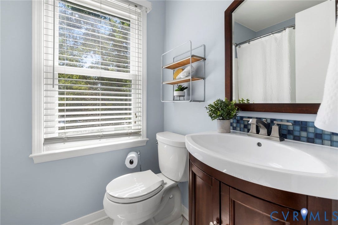 2308 Strangford Court, Henrico, VA 23233 Curved-front vanity with a basin sink, wood-finish framed mirror, and mosaic tile backsplash