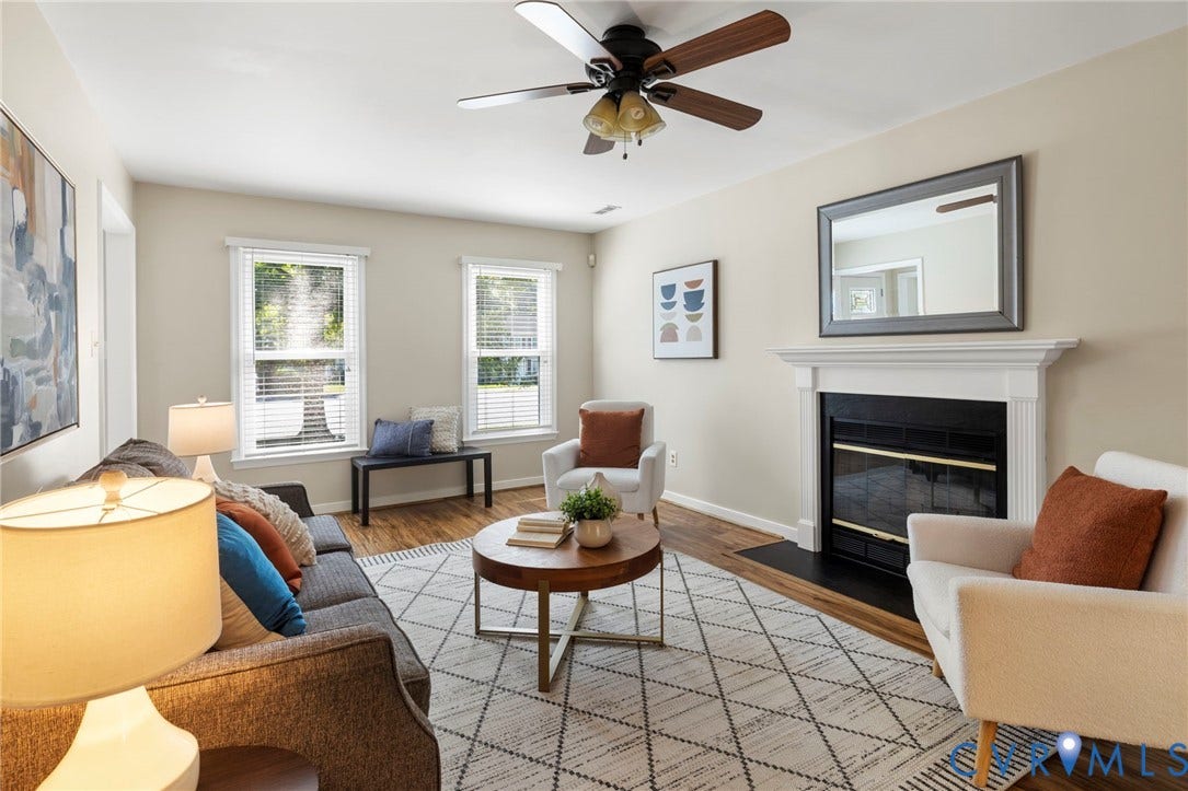 2308 Strangford Court, Henrico, VA 23233 Living space featuring wood-finish flooring, two large windows with blinds, a ceiling fan, and a fireplace with a white mantel and black hearth