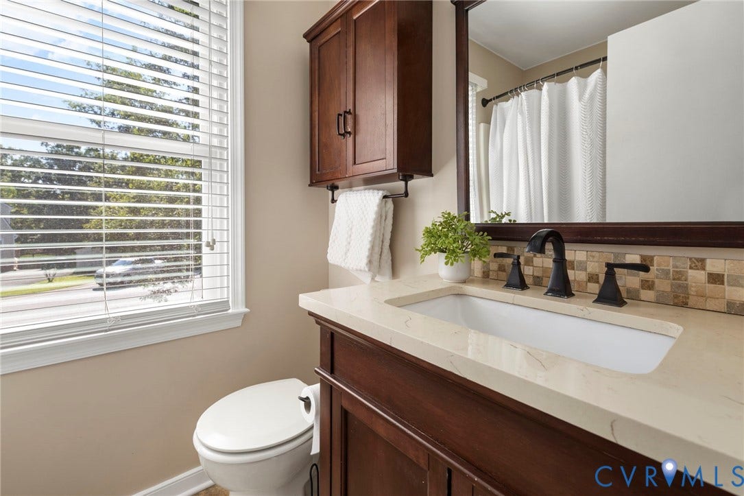 2308 Strangford Court, Henrico, VA 23233 Wood-finish vanity with an integrated rectangular sink, light-toned countertop, and matte black faucet