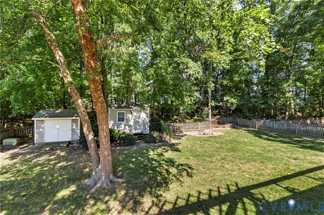 2308 Strangford Court, Henrico, VA 23233 Expansive backyard featuring a manicured lawn, two detached storage sheds, and a perimeter fence