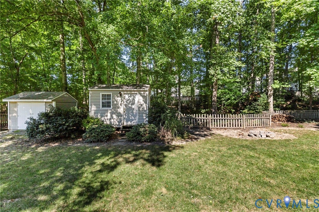 2308 Strangford Court, Henrico, VA 23233 Expansive backyard featuring two exterior storage sheds, mature trees, and a wooden picket fence