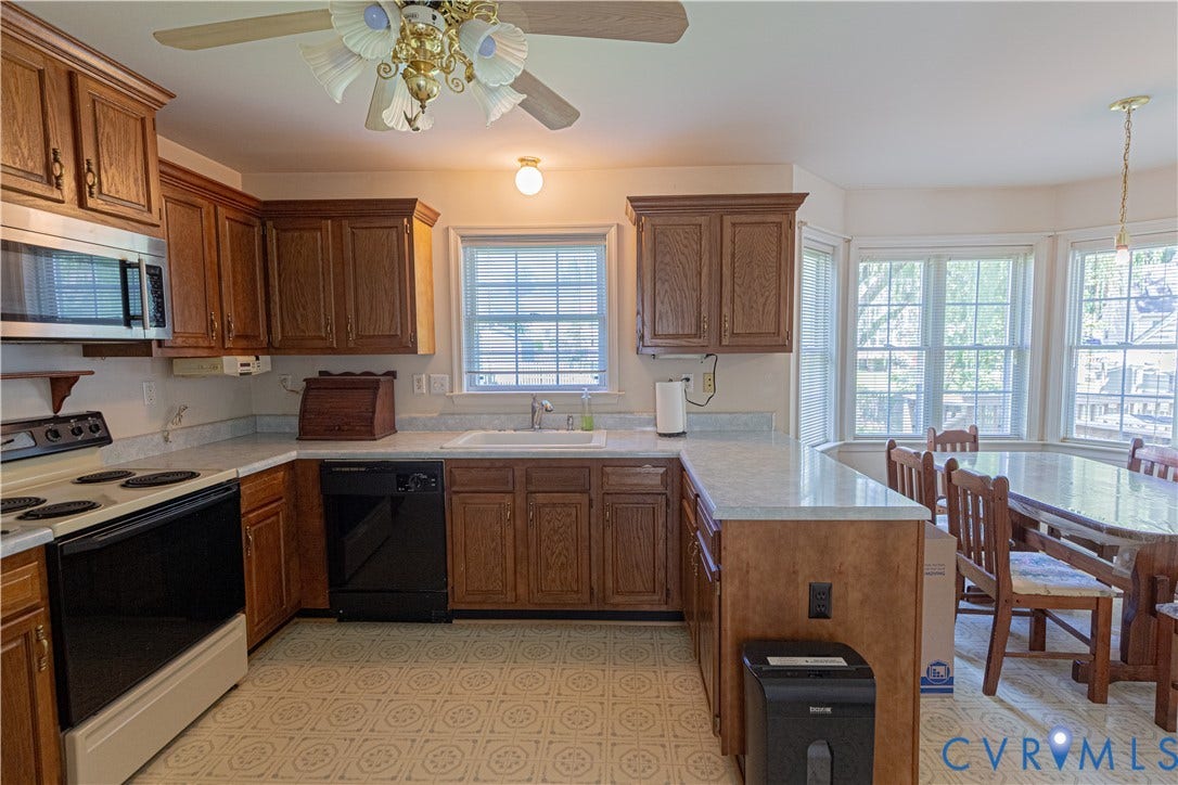 Kitchen featuring wood cabinetry, light-toned countertops, a built-in microwave, and a ceiling fan