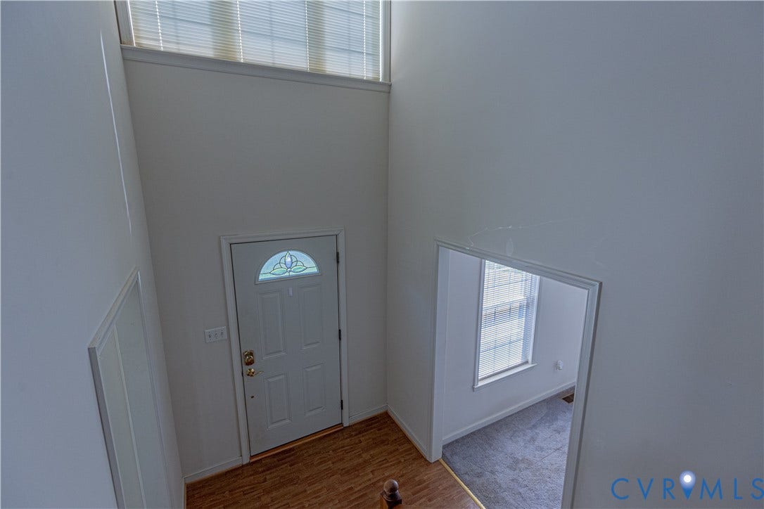 Two-story foyer featuring a transom window, decorative glass front door, and wood-finish flooring