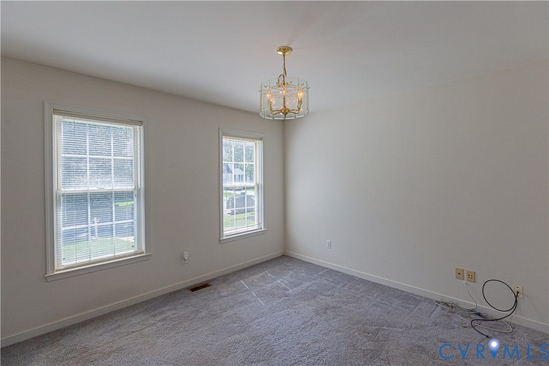 Wall-to-wall carpeting, two double-hung windows with blinds, and a gold-finish flush mount light fixture