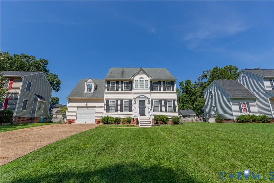 Two-story residence featuring light-toned siding, a dormer window, and an attached garage