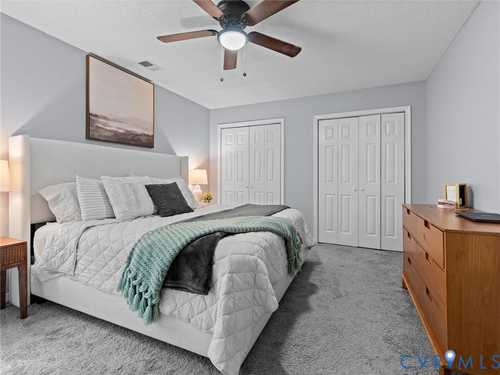 6712 N Hedges Road, Chesterfield, VA 23224 Carpeted bedroom featuring a ceiling fan, two bifold door closets, and light gray wall paint