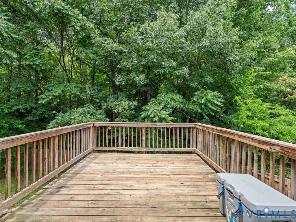 6712 N Hedges Road, Chesterfield, VA 23224 Expansive wooden deck with a slatted railing, surrounded by mature trees and lush green foliage