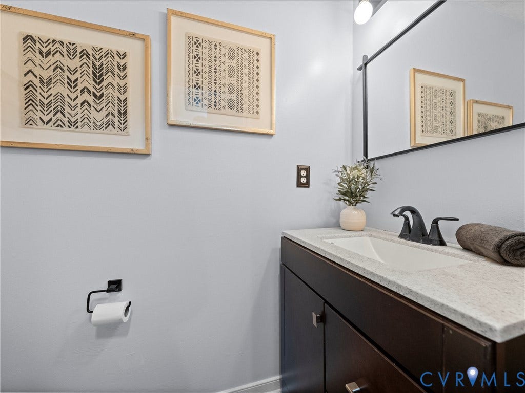 6712 N Hedges Road, Chesterfield, VA 23224 Bathroom vanity featuring a dark wood-finish cabinet with silver-tone hardware, a white undermount sink, and a light-toned countertop
