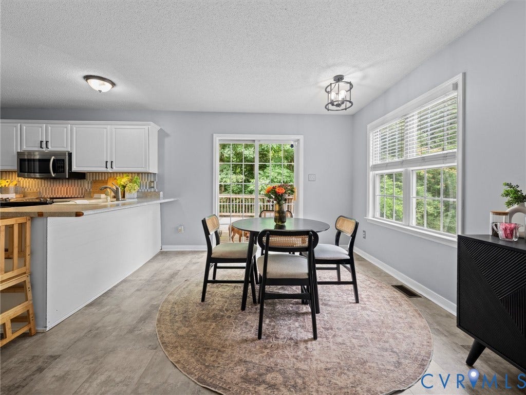 6712 N Hedges Road, Chesterfield, VA 23224 Eat-in kitchen featuring wood-finish flooring, white cabinetry, stainless steel microwave, and tiled backsplash