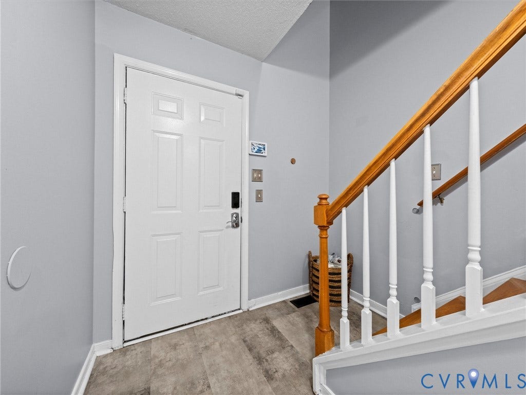 6712 N Hedges Road, Chesterfield, VA 23224 Entryway featuring a paneled door with smart lock hardware, wood-finish flooring, and a staircase with a natural wood handrail and white balusters