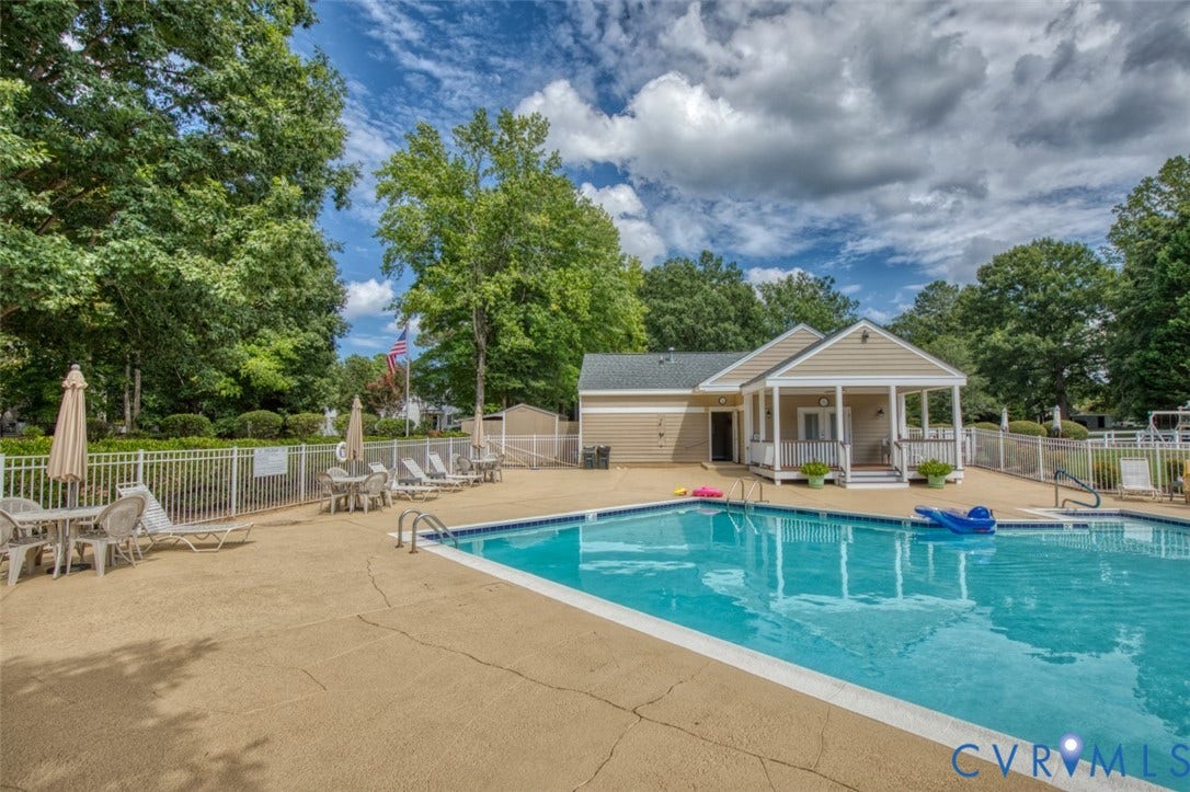 6311 Chiswick Park, Williamsburg, VA 23188 Resort-style swimming pool with crystal-blue water and concrete decking, anchored by a single-story pool house with covered portico and columns