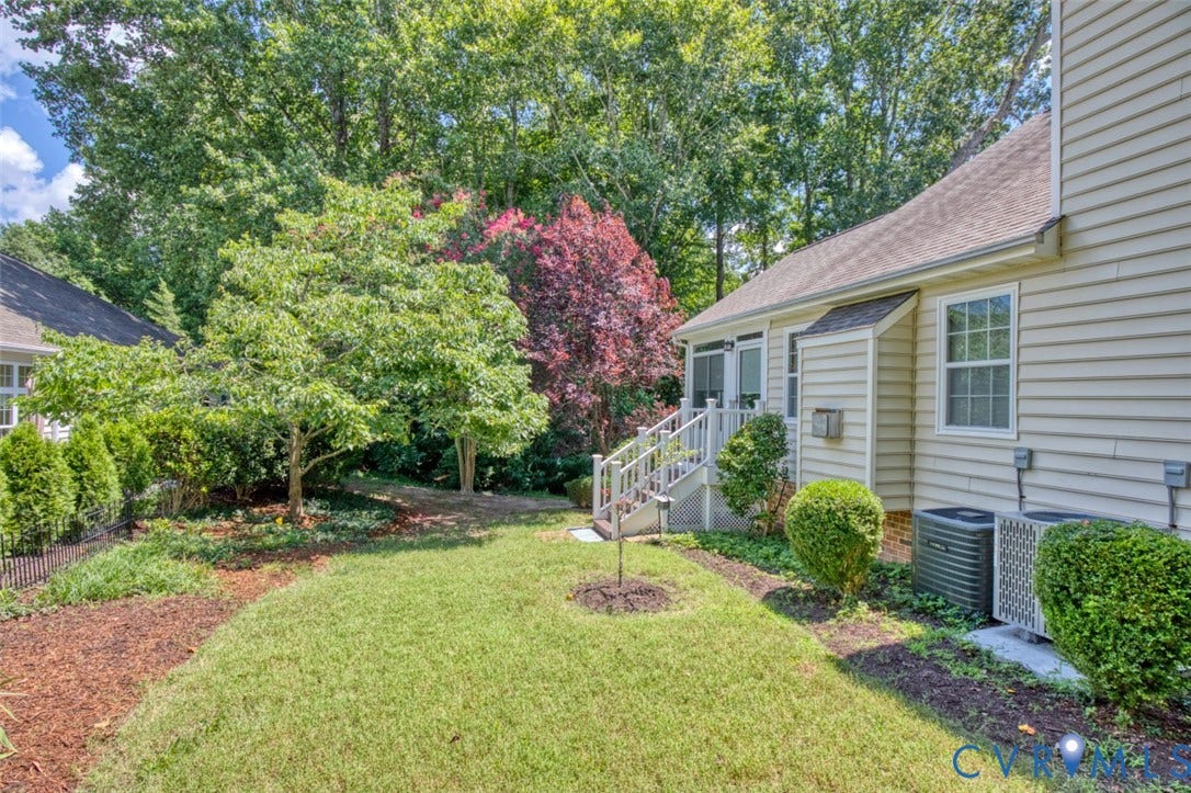 6311 Chiswick Park, Williamsburg, VA 23188 Manicured grounds featuring a lush lawn, mature landscaping with flowering trees, and thoughtfully designed planting beds with mulch borders